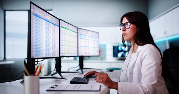 Clinician reviewing revenue cycle dashboards across multiple screens